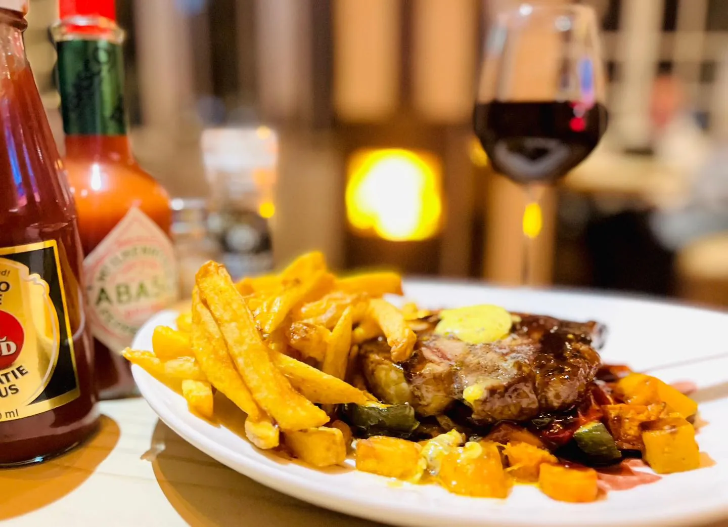 Grilled sirloin with herb butter and chips by candlelight, with a glass of red